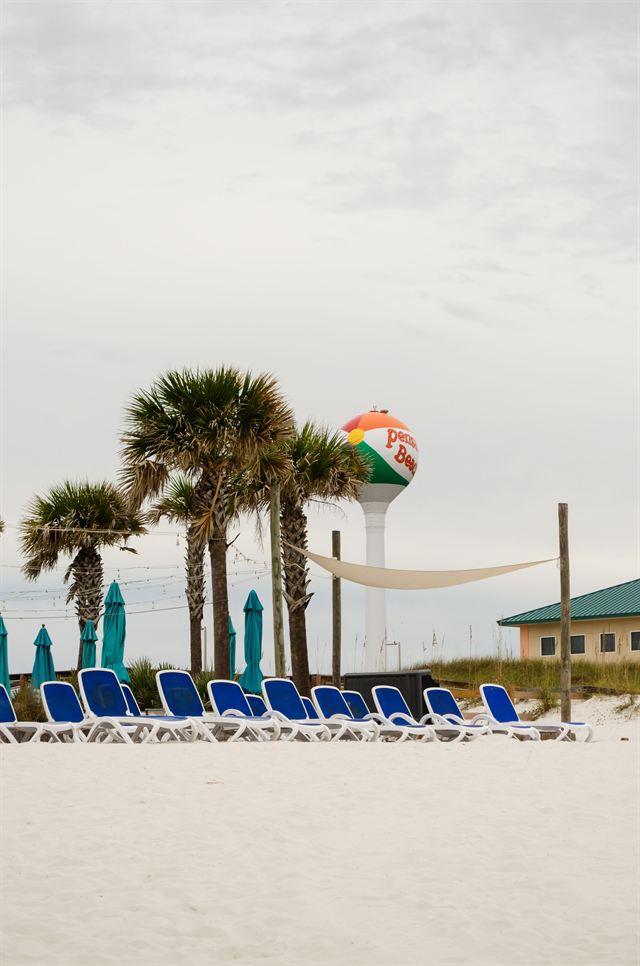 Pensacola Beach with blue sun loungers, palm trees and the Pensacola Beach Ball water tower