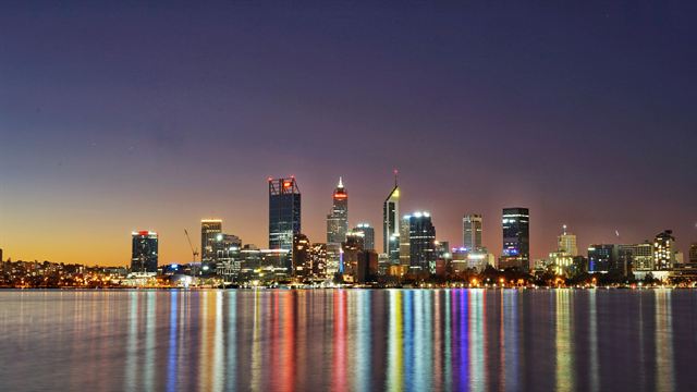 Perth city skyline lit at dusk and reflected in colorful streaks across the Swan River