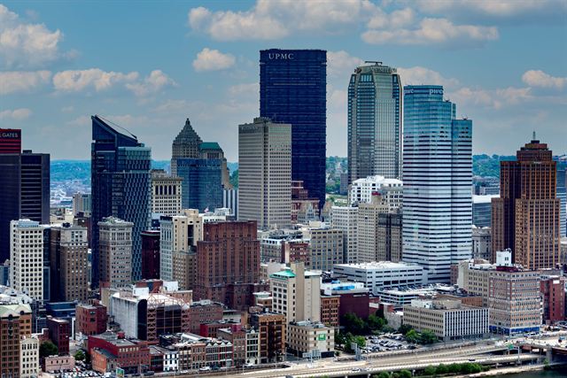 Cluster of downtown Pittsburgh office towers including PPG Place and the UPMC tower under blue sky