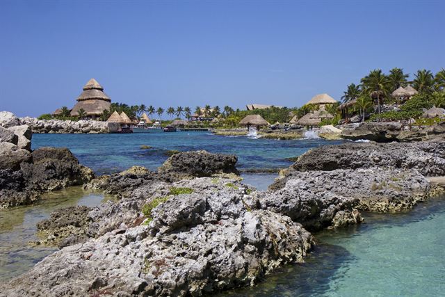 Rocky Caribbean shoreline and thatched palapas at Xcaret, just south of Playa del Carmen, Mexico