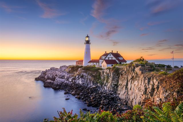 Portland Head Light lighthouse and keeper's house on rocky cliffs at sunset, Cape Elizabeth, Maine