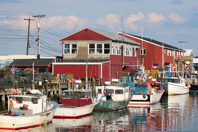 Lobster and fishing boats moored beside red-sided wharf buildings on the Portland, Maine waterfront