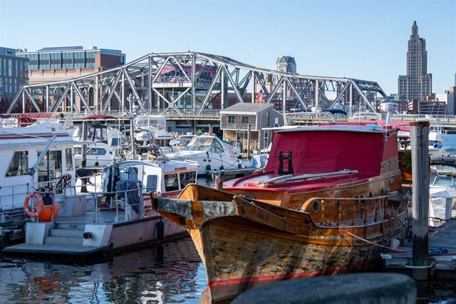 Boats at a Providence marina with a steel truss bridge and the downtown skyline behind
