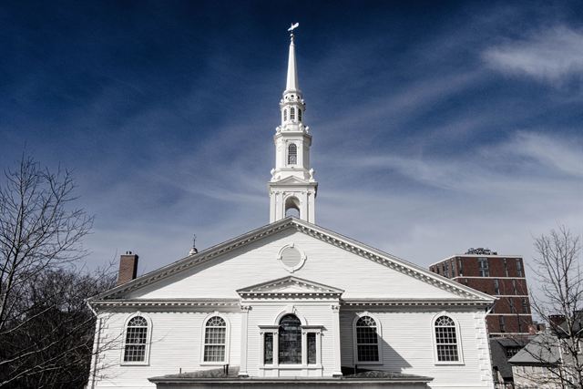 White steeple and facade of the First Baptist Meeting House in Providence under a dramatic sky