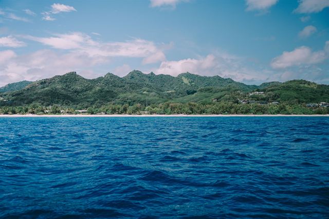 Green mountainous skyline of Rarotonga in the Cook Islands above deep blue ocean