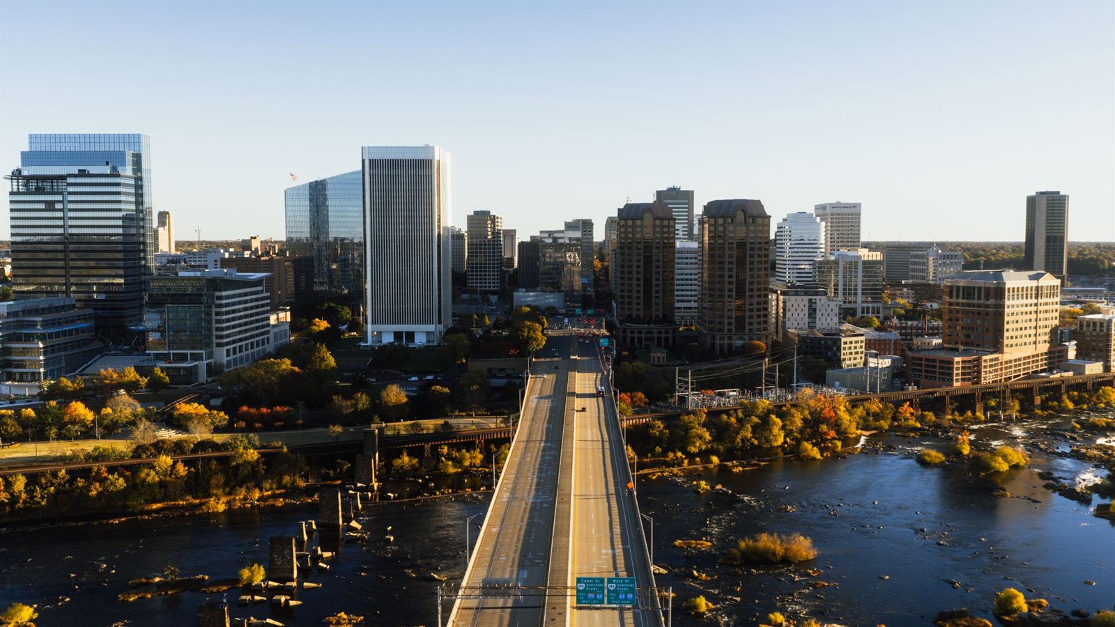 Aerial view of downtown Richmond, Virginia skyline with a bridge crossing the rocky James River at dusk