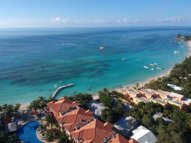 Aerial view of West Bay Beach on Roatan with turquoise Caribbean water, boats and red-roofed resort buildings