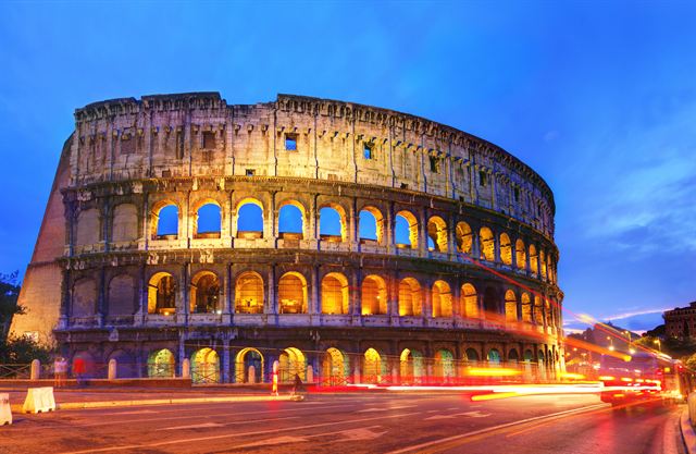 The Colosseum lit at night with traffic light trails