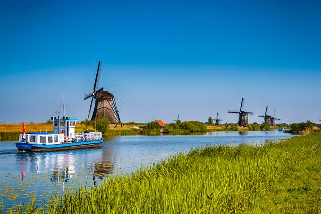 Tour boat on a canal lined with the historic windmills of Kinderdijk near Rotterdam