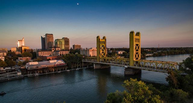 Sacramento's gold Tower Bridge over the Sacramento River with the downtown skyline at sunset