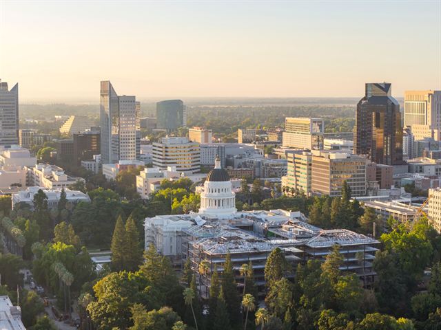 Aerial view of downtown Sacramento with the domed California State Capitol amid trees at dusk