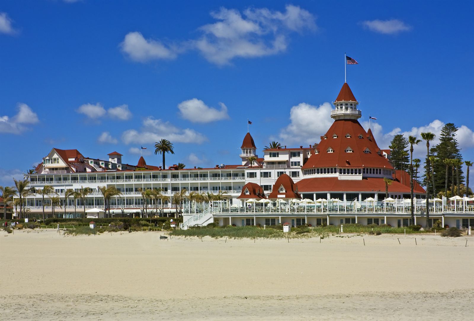 The red-roofed Victorian Hotel del Coronado seen across the sand of Coronado Beach
