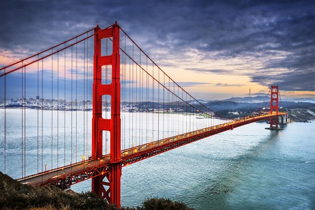 Golden Gate Bridge spanning the bay with low fog at sunset