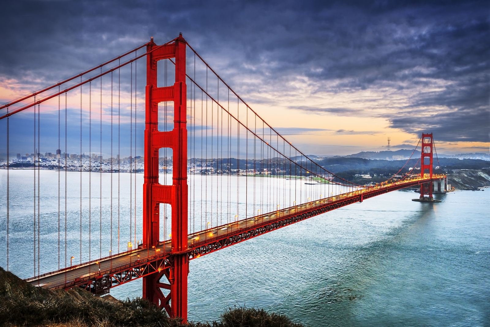 Golden Gate Bridge spanning the bay with low fog at sunset