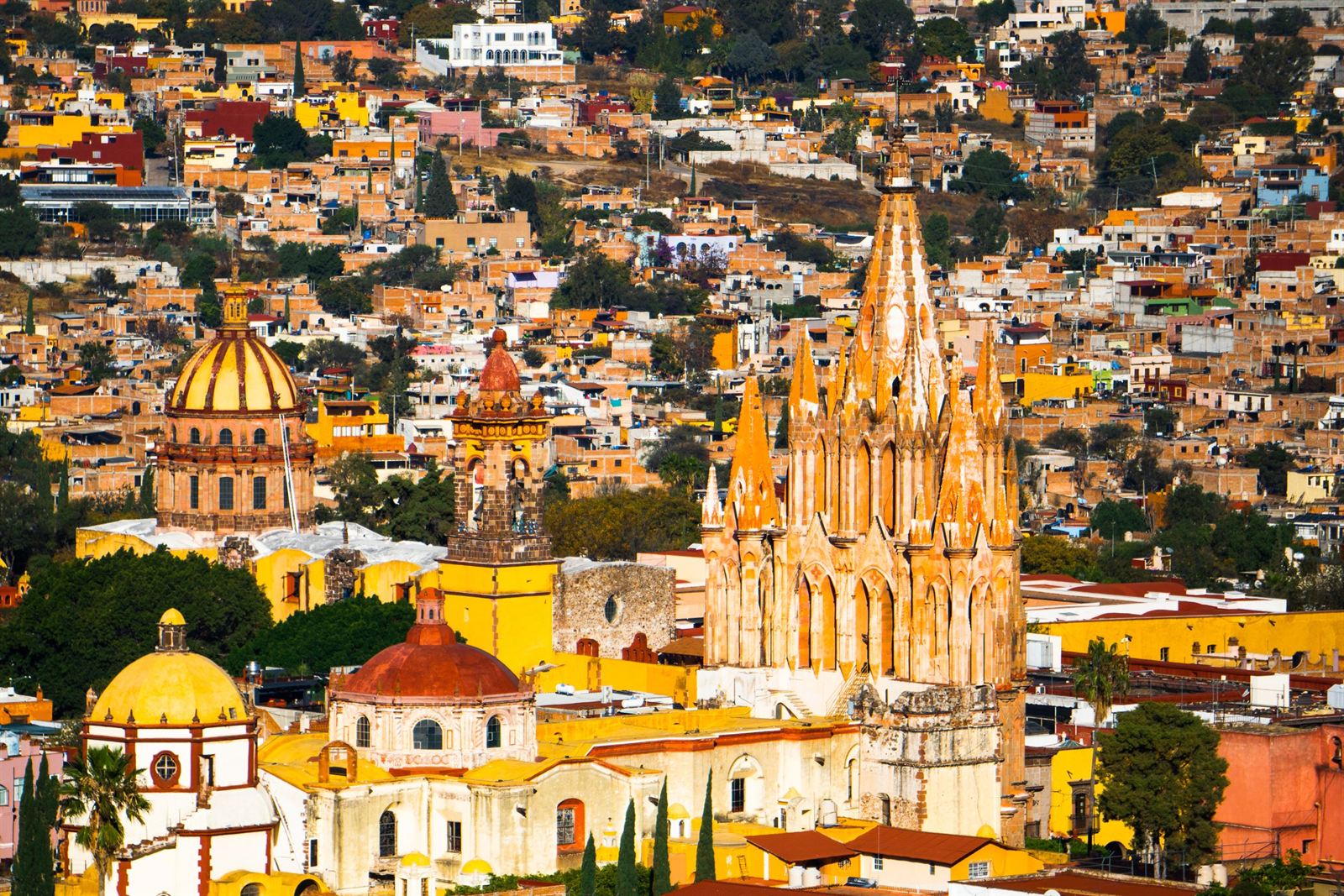 Hilltop view over San Miguel de Allende with the pink Gothic Parroquia spires, domes and colorful colonial rooftops