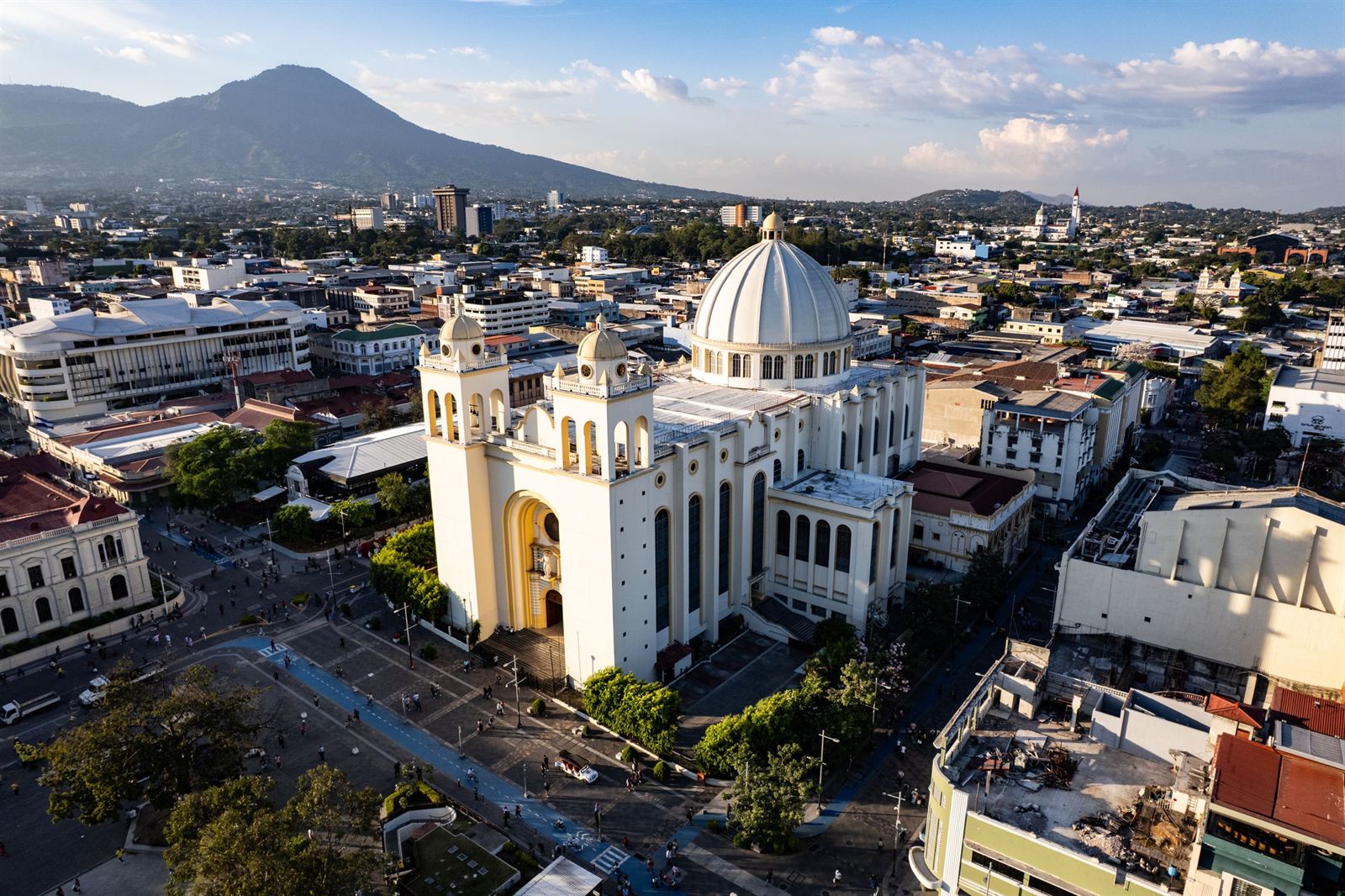 Aerial view of San Salvador's white domed Metropolitan Cathedral amid downtown with the San Salvador volcano behind