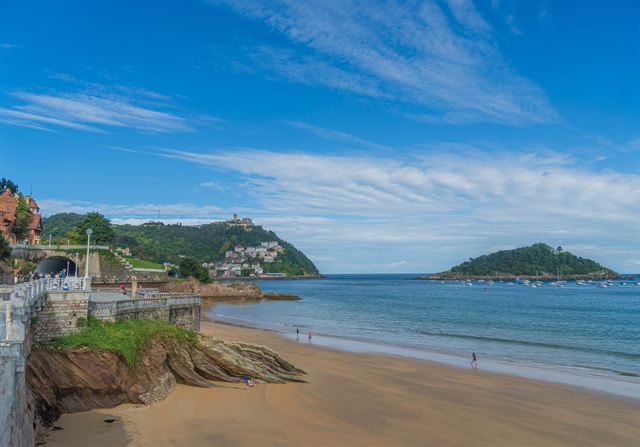 La Concha beach in San Sebastian with Santa Clara island and Monte Urgull under blue sky