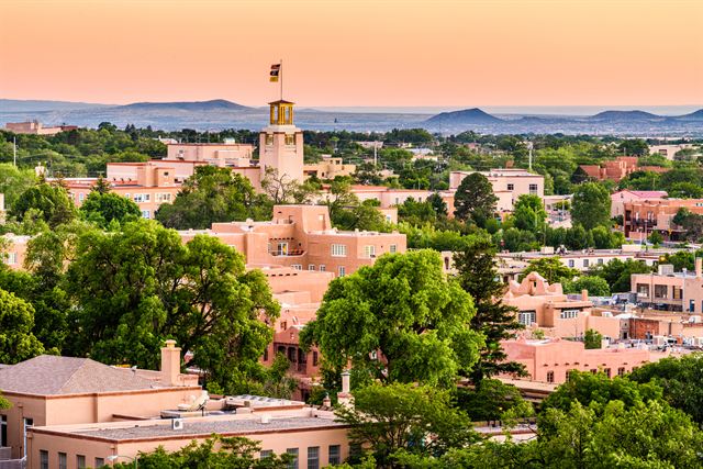 Adobe buildings and trees of downtown Santa Fe at dusk with distant mountains, New Mexico
