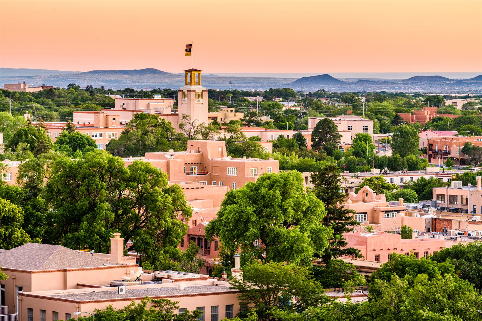 Adobe buildings and trees of downtown Santa Fe at dusk with distant mountains, New Mexico
