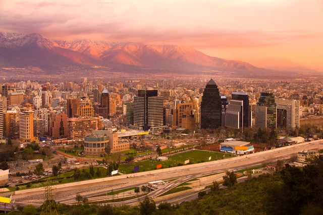 Santiago's city skyline and towers glowing at sunset beneath pink-lit Andes mountains