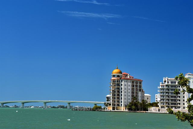 Ringling Causeway bridge and a domed Sarasota high-rise on the bayfront under blue sky