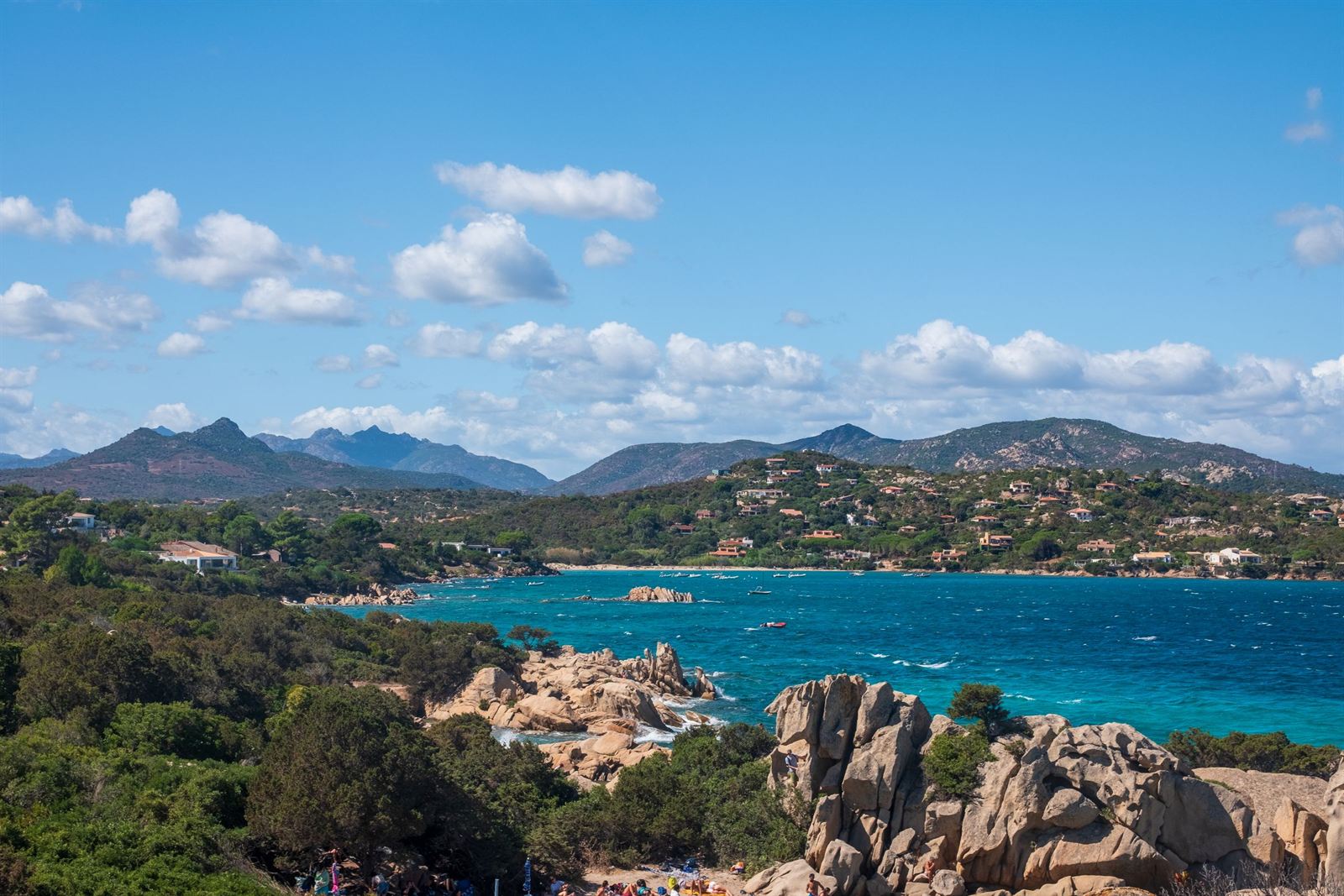 Turquoise bay framed by granite boulders, green maquis and mountains on Sardinia's northeast coast