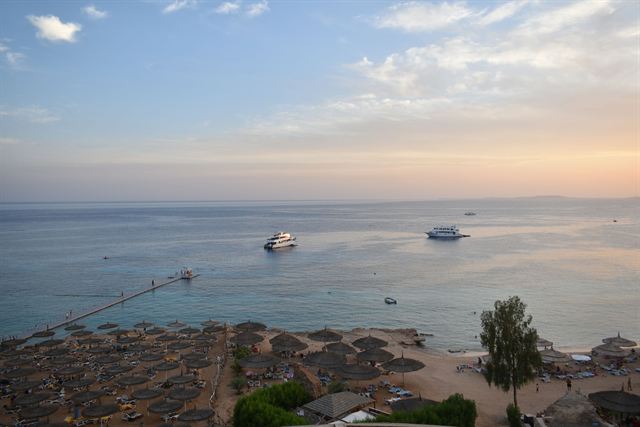 Red Sea coastline at Sharm El Sheikh with dive boats, jetty and beach umbrellas at dusk