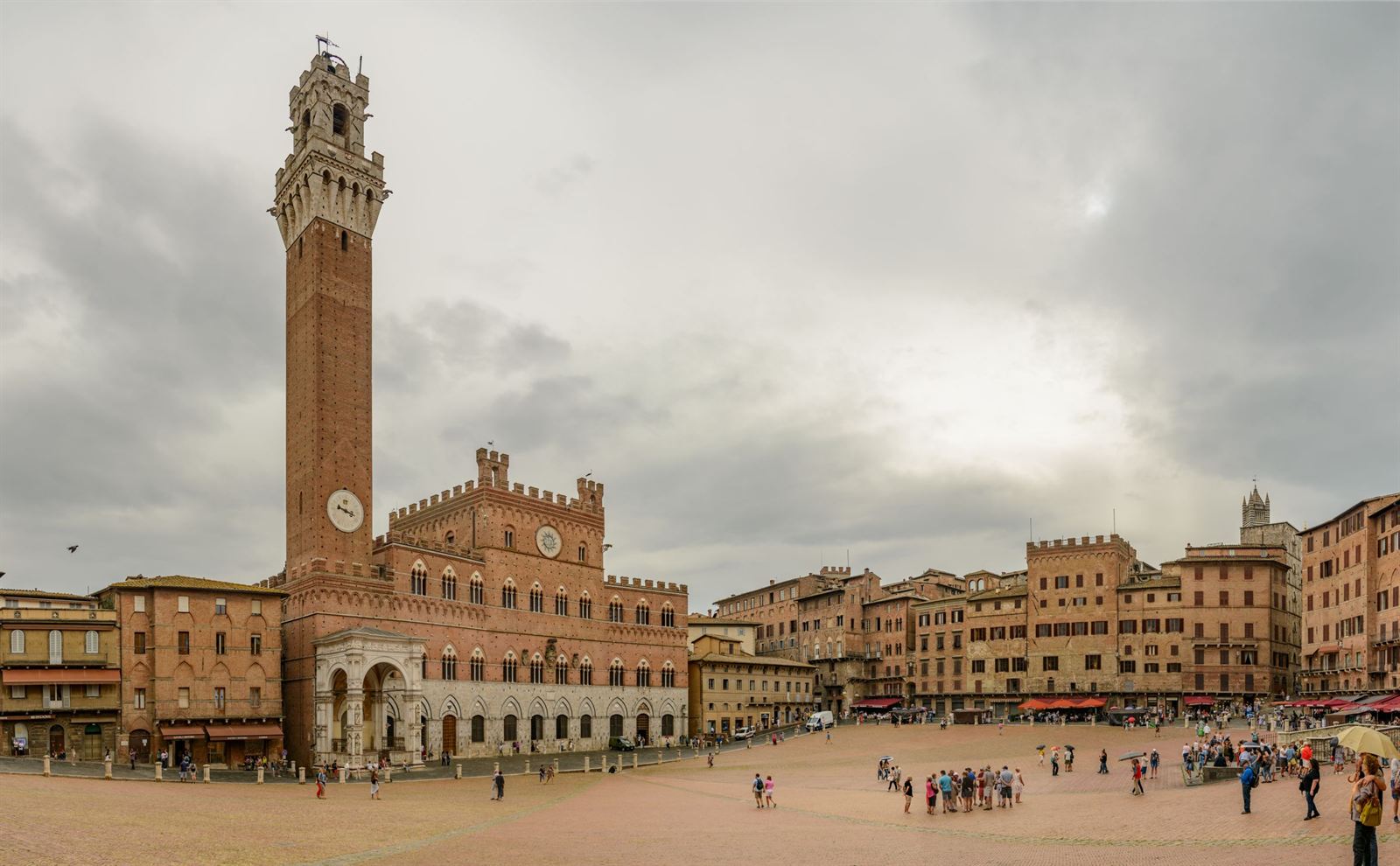Piazza del Campo in Siena with the Palazzo Pubblico and tall Torre del Mangia under clouds