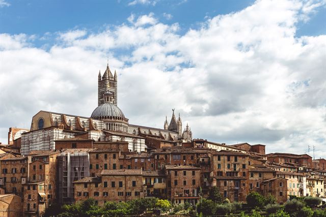 Siena's hilltop skyline of brick medieval houses crowned by the striped cathedral bell tower and dome