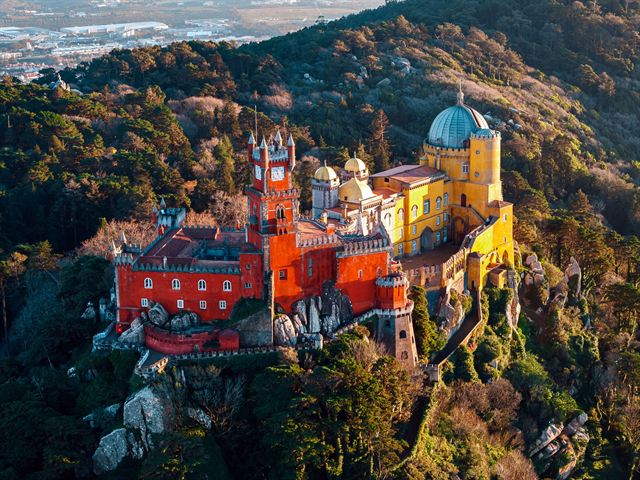 Aerial view of colorful Pena Palace on its forested hill above Sintra