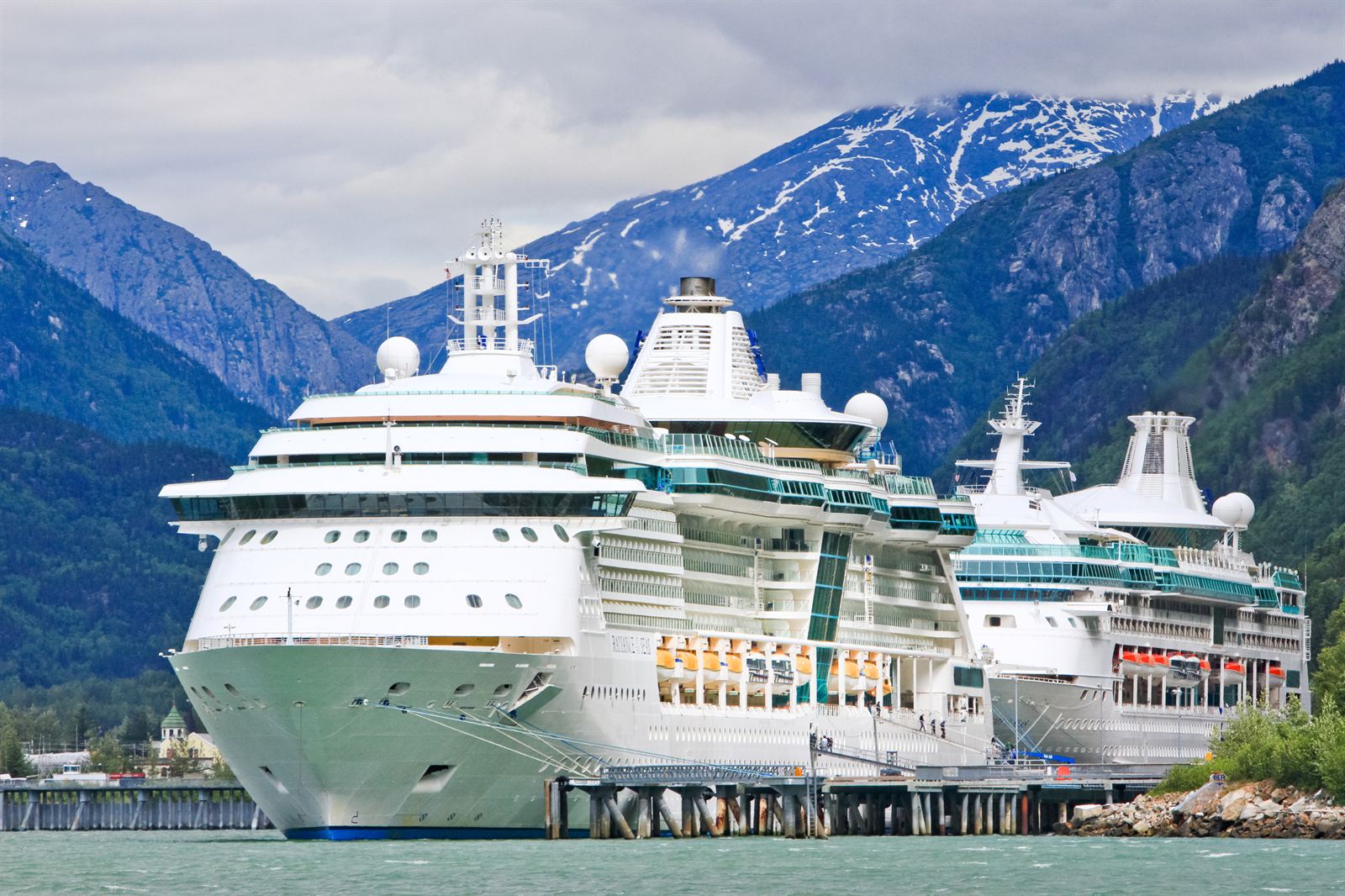 Two large cruise ships docked at Skagway below snow-streaked mountains, Alaska