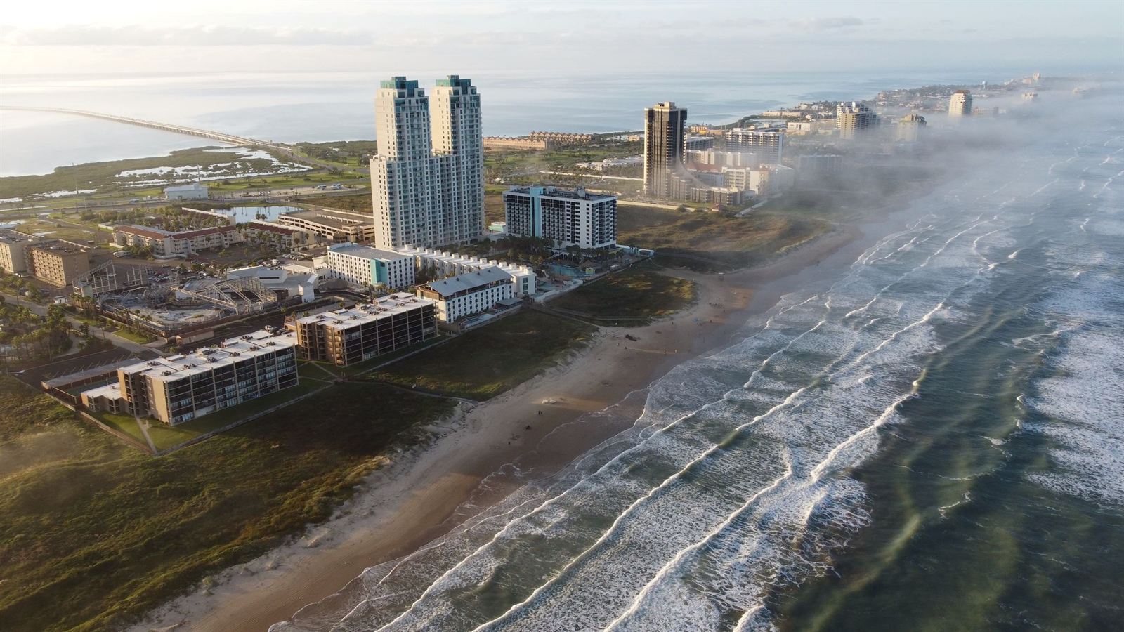 Aerial view of South Padre Island beachfront condo towers and hotels above the Gulf surf in morning haze