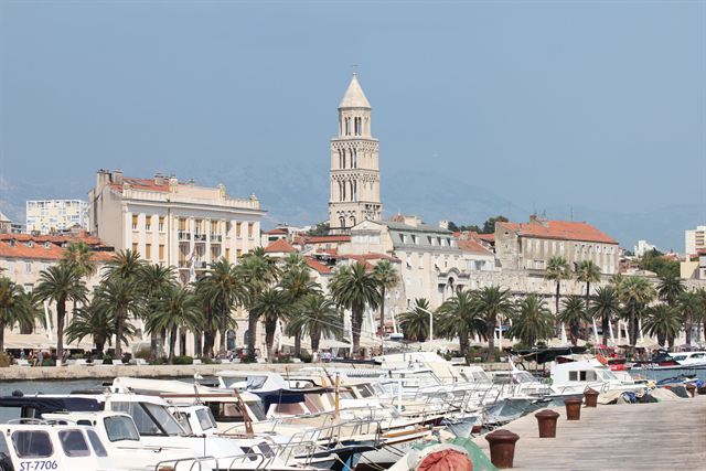 Bell tower of the Cathedral of Saint Domnius rising over palm-lined Split harbor and moored boats
