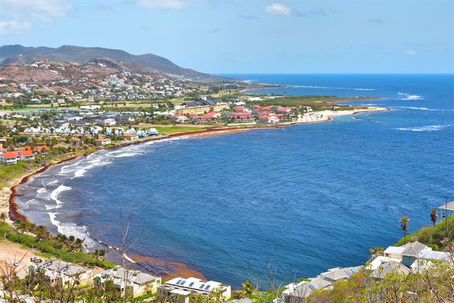 Hillside view of the curving Frigate Bay beach and resort area on St Kitts with deep blue sea
