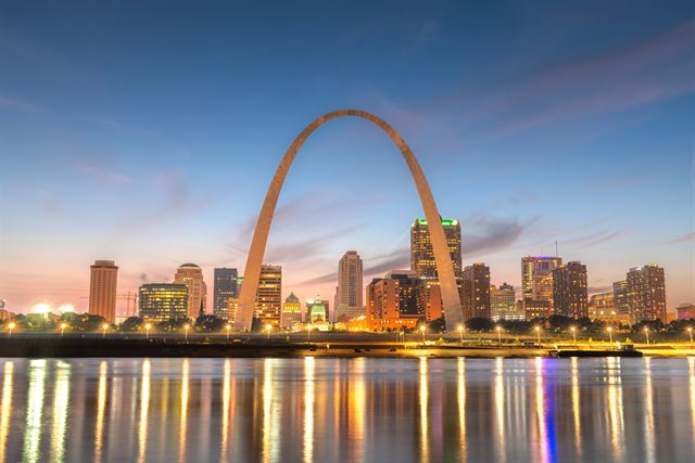 Gateway Arch and downtown St. Louis skyline lit at dusk, reflected in the Mississippi River