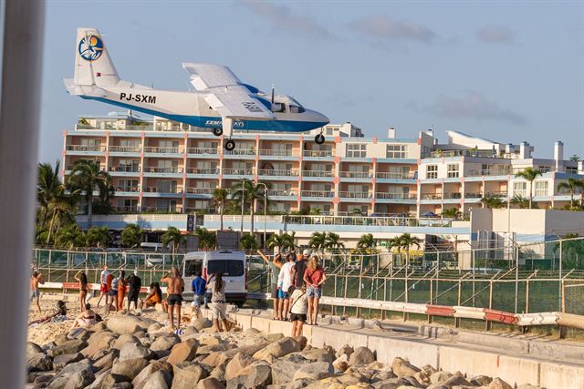 Low-flying plane passing over spectators on the rocks of Maho Beach beside Princess Juliana Airport, St. Maarten