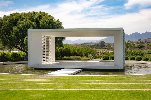 Modern open pavilion by a pond with lawns and mountain views at Hazendal Wine Estate, Stellenbosch