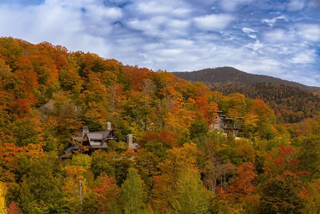 Aerial view of Stowe, Vermont hillsides blanketed in red, orange and gold autumn foliage with chalets