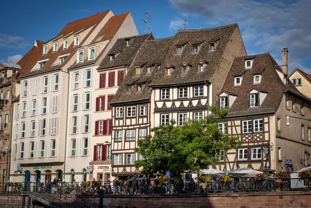Tall half-timbered Alsatian houses with steep roofs along the riverside in Strasbourg