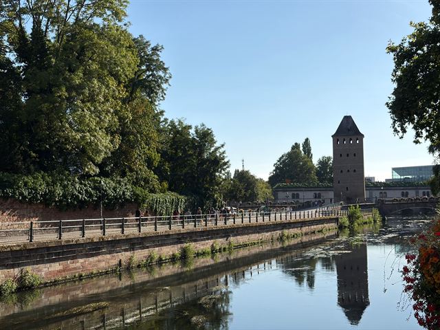 Medieval tower of the Ponts Couverts in Strasbourg reflected in the Ill river on a sunny day