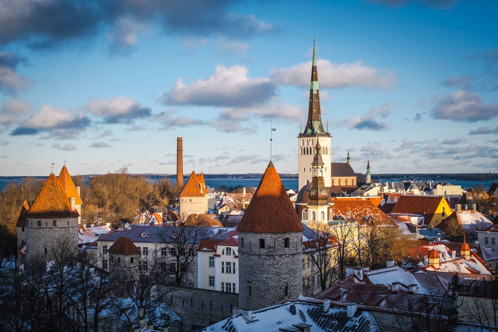Tallinn Old Town towers, orange-roofed wall turrets and St. Olaf's Church spire under blue sky