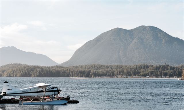 Floatplane moored on calm water near Tofino with forested islands and mountains behind