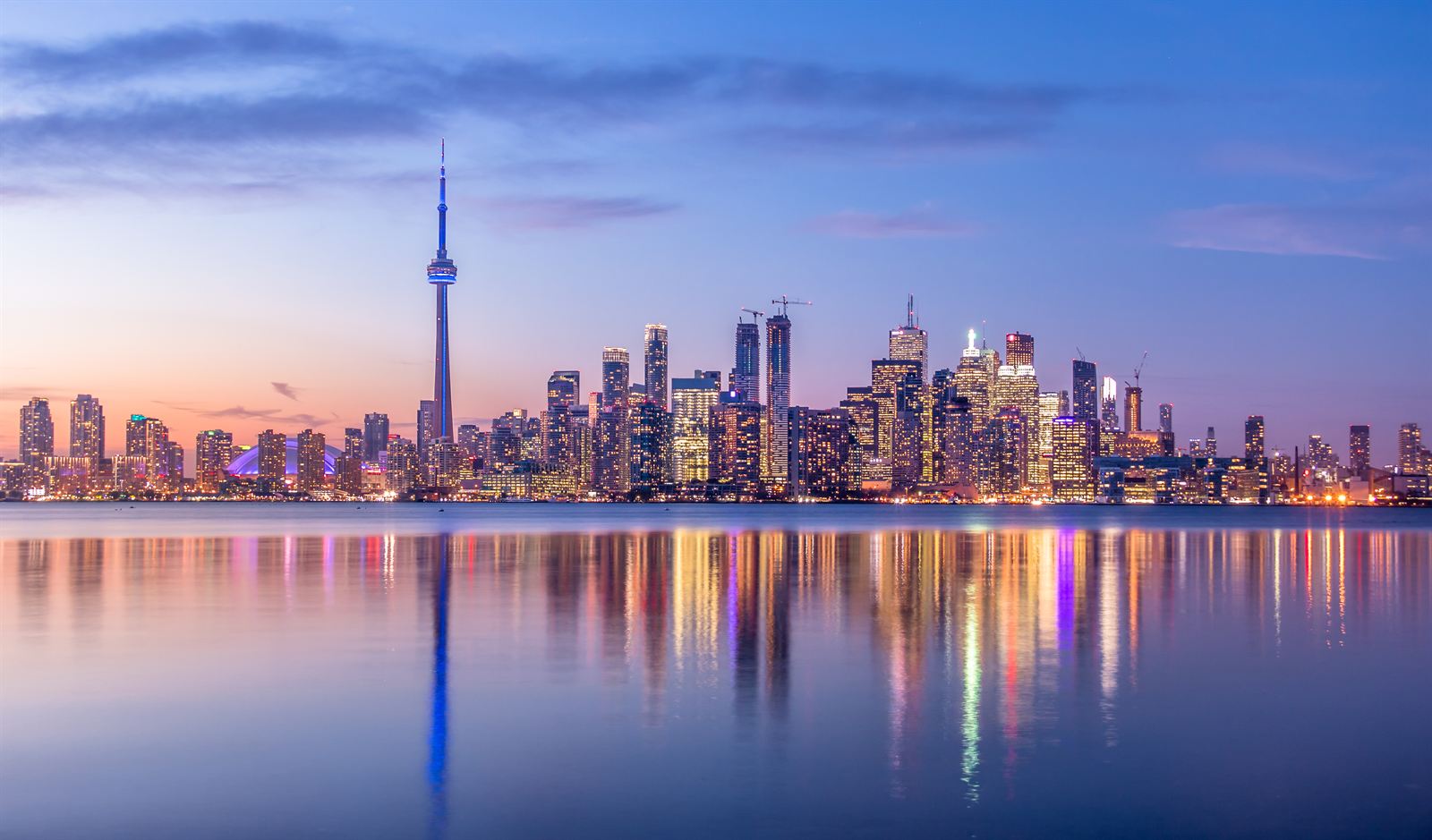 Toronto skyline with the CN Tower reflected in Lake Ontario under a purple dusk sky