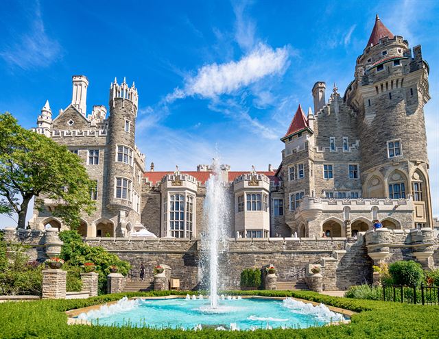 Casa Loma's Gothic Revival castle towers above its garden fountain on a sunny day in Toronto