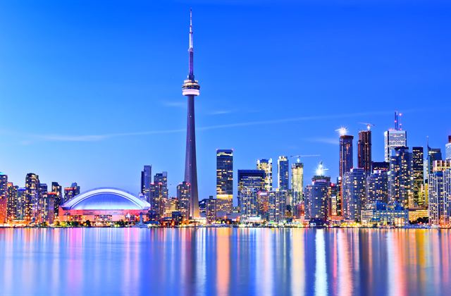 Night skyline of Toronto with the CN Tower and Rogers Centre dome reflected in the harbour