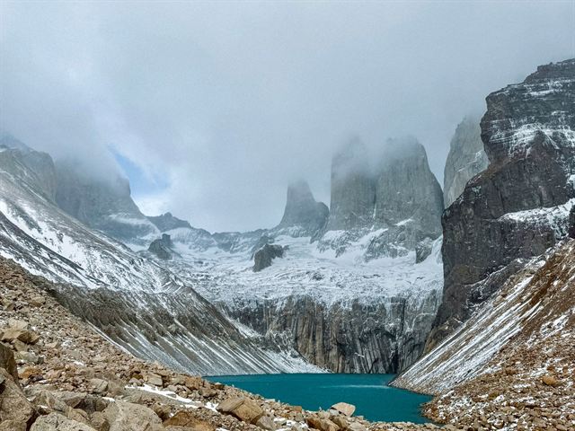 The three granite towers of Torres del Paine above a glacial lagoon with snow on the slopes