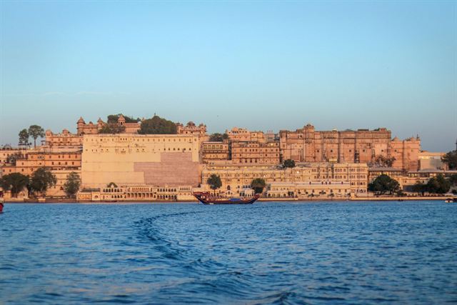 City Palace of Udaipur glowing in golden light along the shore of Lake Pichola