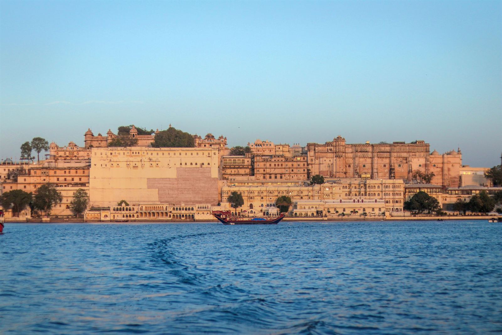 City Palace of Udaipur glowing in golden light along the shore of Lake Pichola