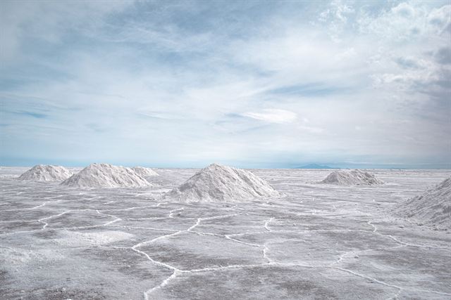 Conical salt piles on the white Salar de Uyuni salt flat under a pale blue sky