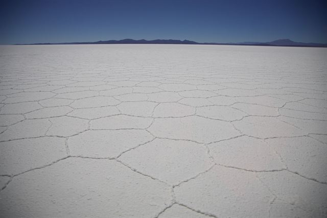 Hexagonal salt crust patterns stretching to the horizon across Salar de Uyuni, Bolivia
